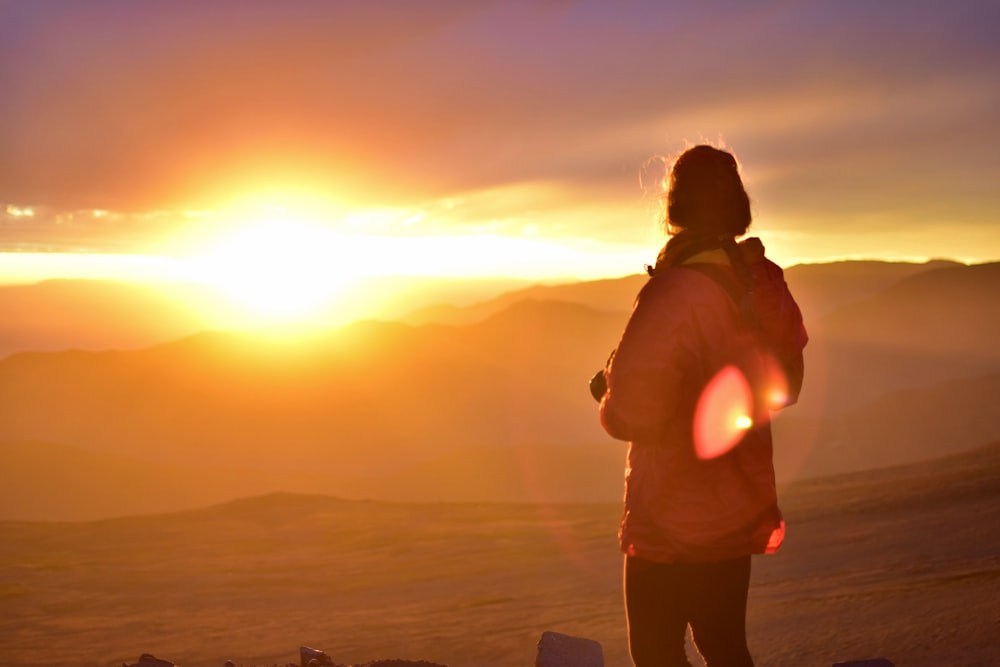 person standing on mountain under sunset