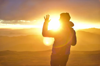 A sunrise symbolizing new beginnings with a person standing confidently on a hilltop.