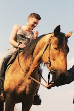 A smiling person gently riding a horse during a therapy session.
