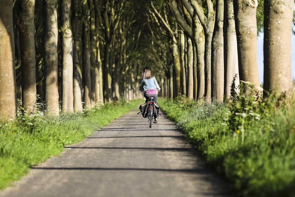 Frau radelt auf dem Weg unter Baumtunnel