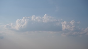 A large, fluffy white cloud floating in a clear blue sky with a soft gradient towards the horizon.