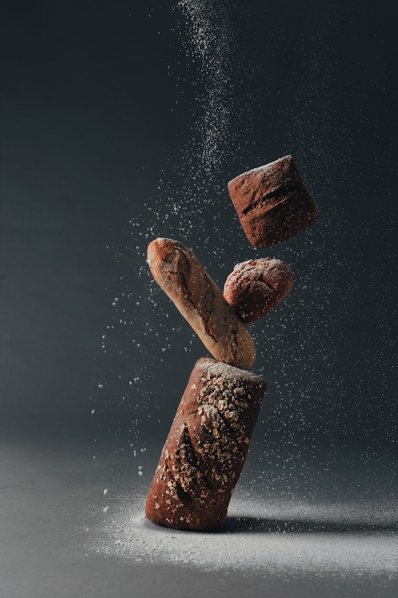 Rustic loaves of bread dusted with falling flour against a dark background