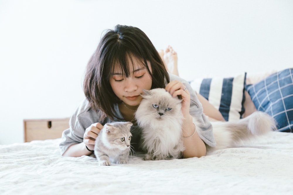 Mujer acostada junto a dos gatitos