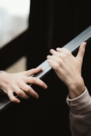 Two hands are reaching towards each other with an emotional and gentle gesture. The surroundings are blurred, focusing attention on the hands.