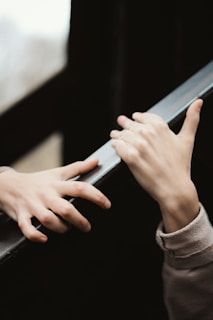 Two hands are reaching towards each other with an emotional and gentle gesture. The surroundings are blurred, focusing attention on the hands.