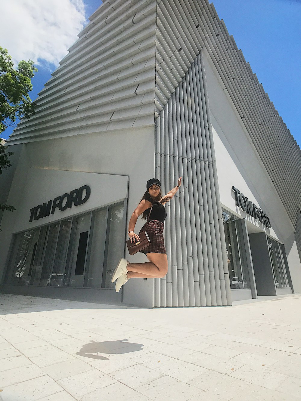 donna che salta vicino all'edificio di Tom Ford durante il giorno