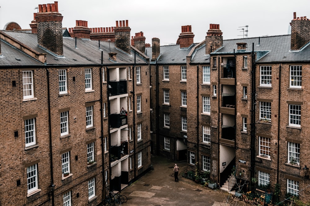 person standing near brown buildings during daytime