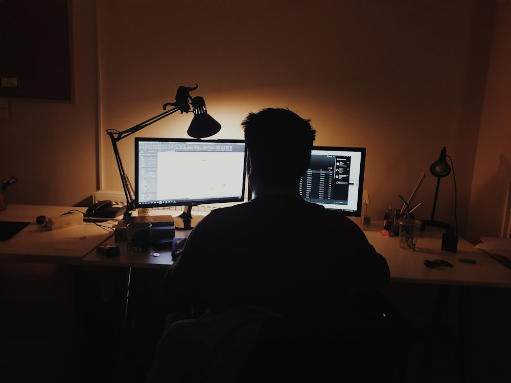 man using computer inside dark room