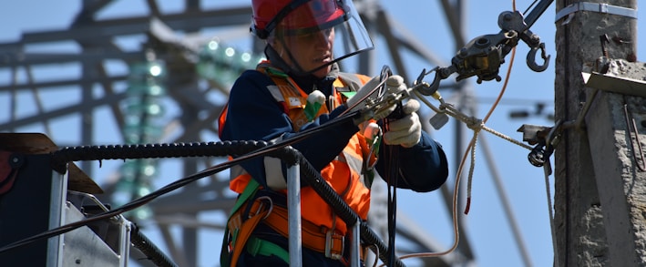 shallow focus photo of man fixing steel cable