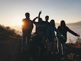 A group of happy travelers posing at a scenic hilltop during sunset.