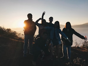 A group of friends taking photos against a stunning sunset backdrop.