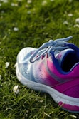 close up photo of blue and pink running shoe on green grass