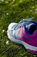 close up photo of blue and pink running shoe on green grass