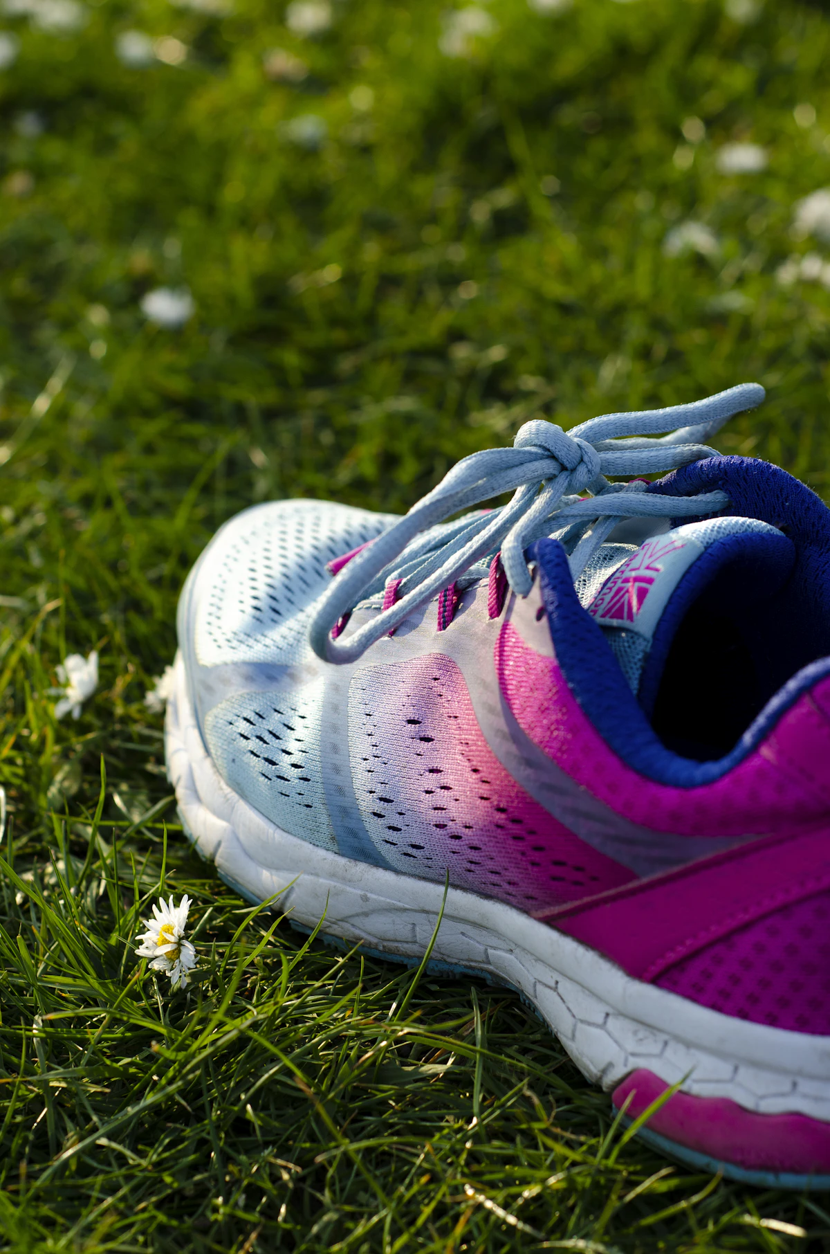 Blue and pink children's running shoe resting on green grass