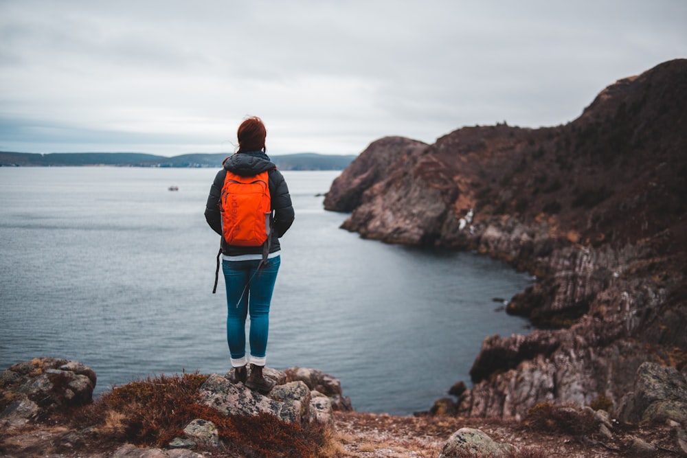 person standing on rock formation near sea during daytime