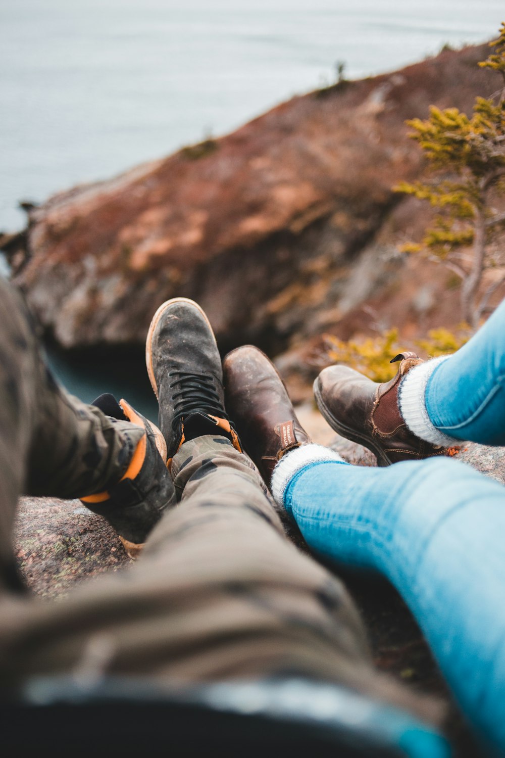 two person sitting on cliff on focus photography