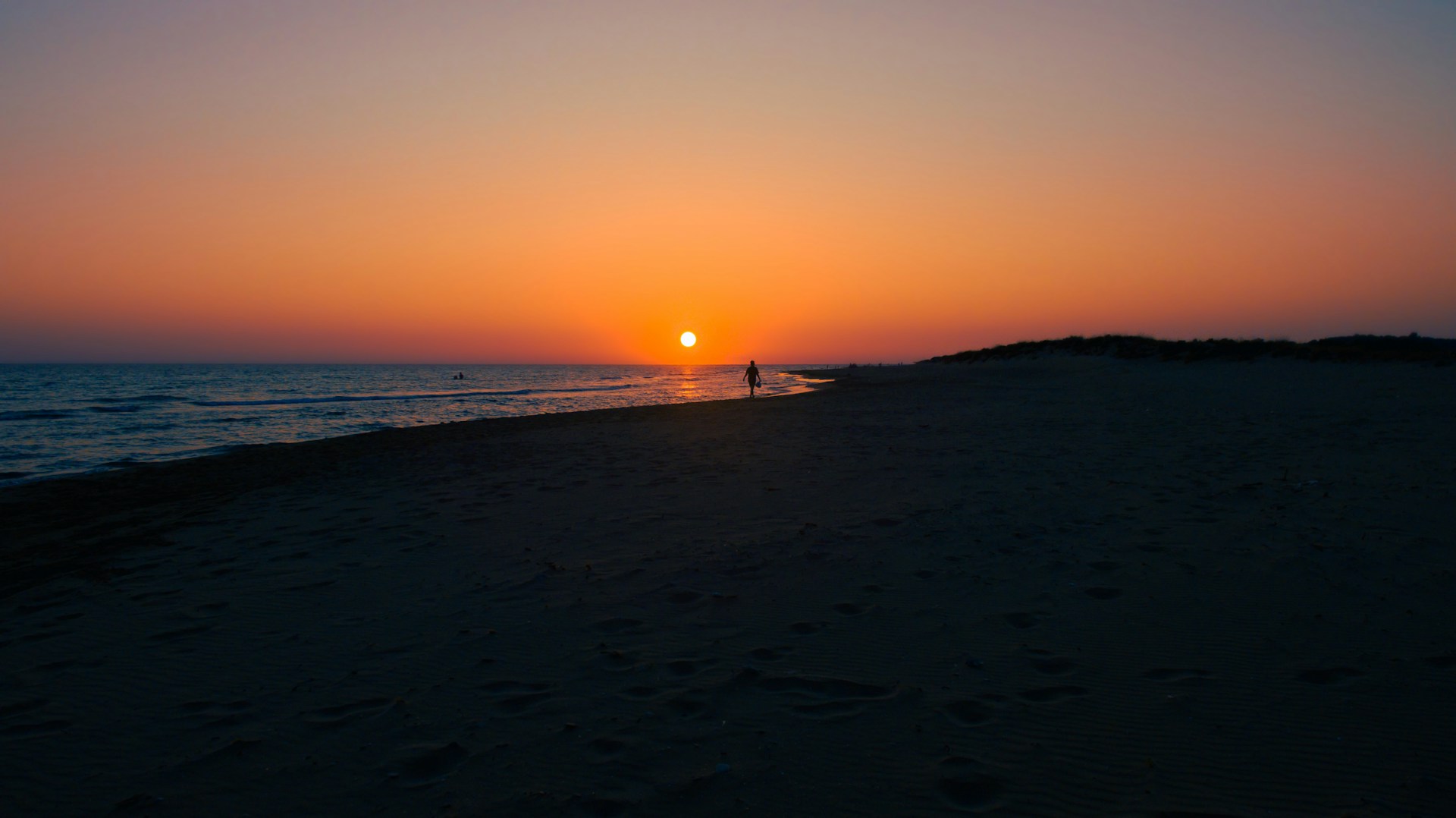 a person standing on a beach at sunset