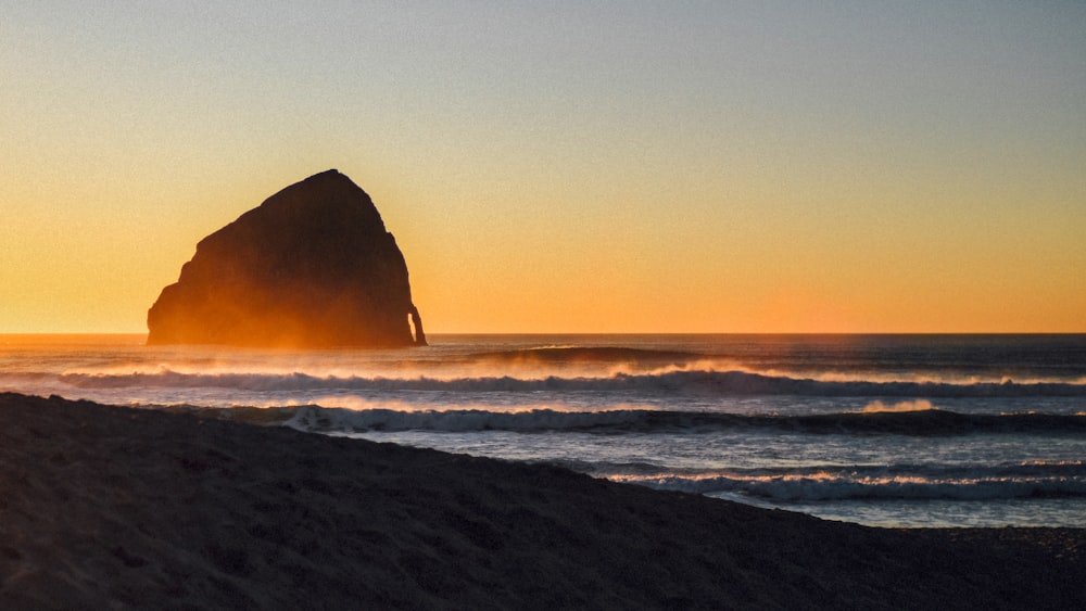 silhouette of rock formation on sea during daytime