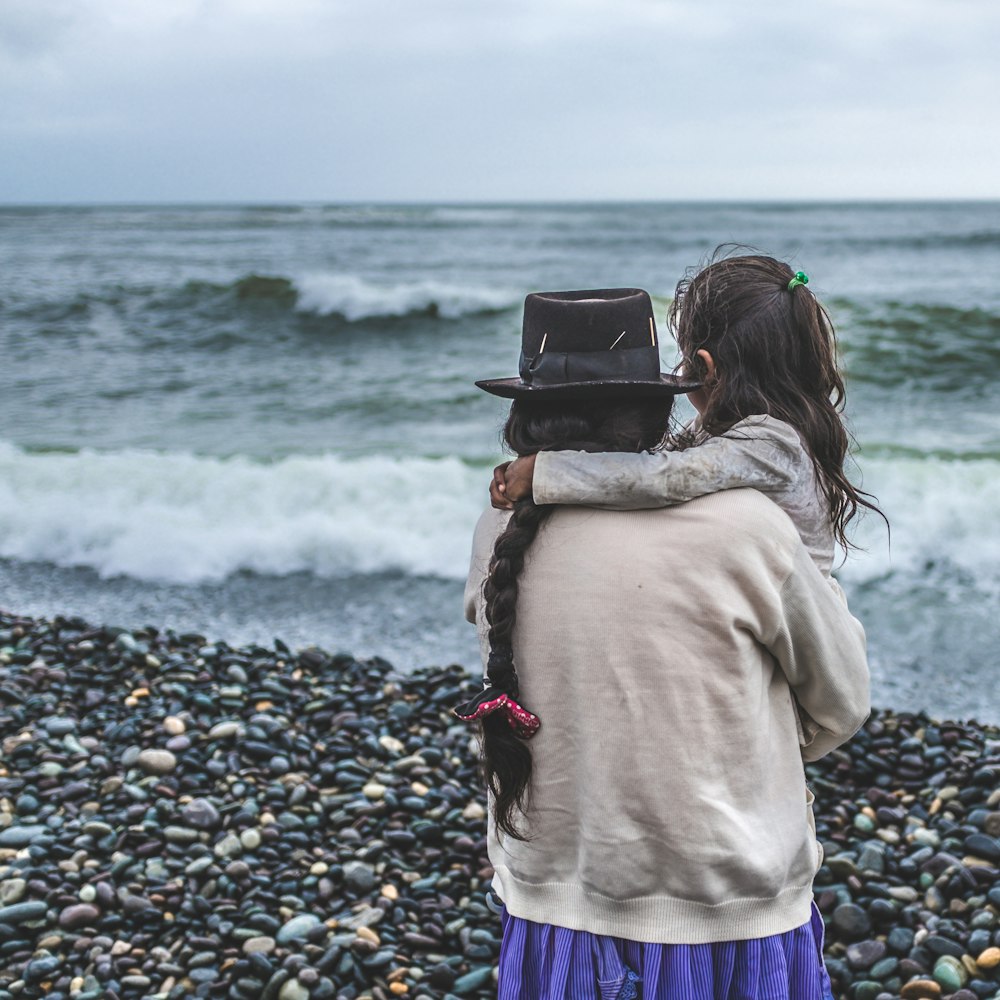 a woman holding a child on a rocky beach