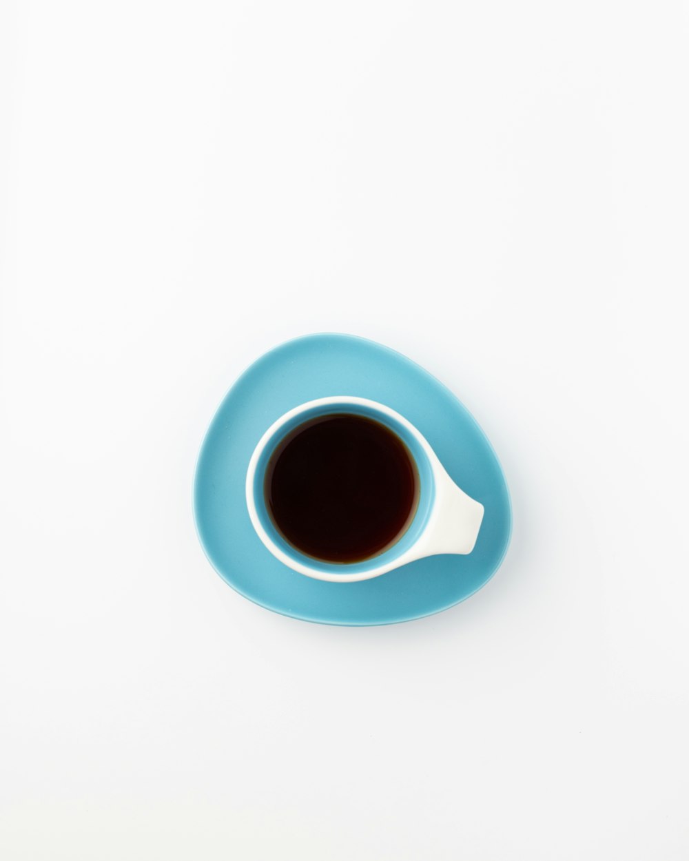 파란 접시 위에 앉아 있는 커피 한 잔