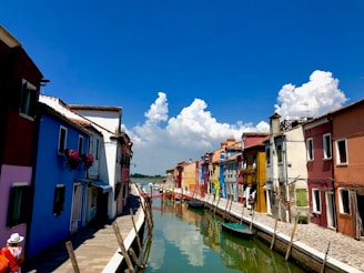 A vibrant canal scene in Amsterdam with colorful houseboats and bicycles lining the waterway.