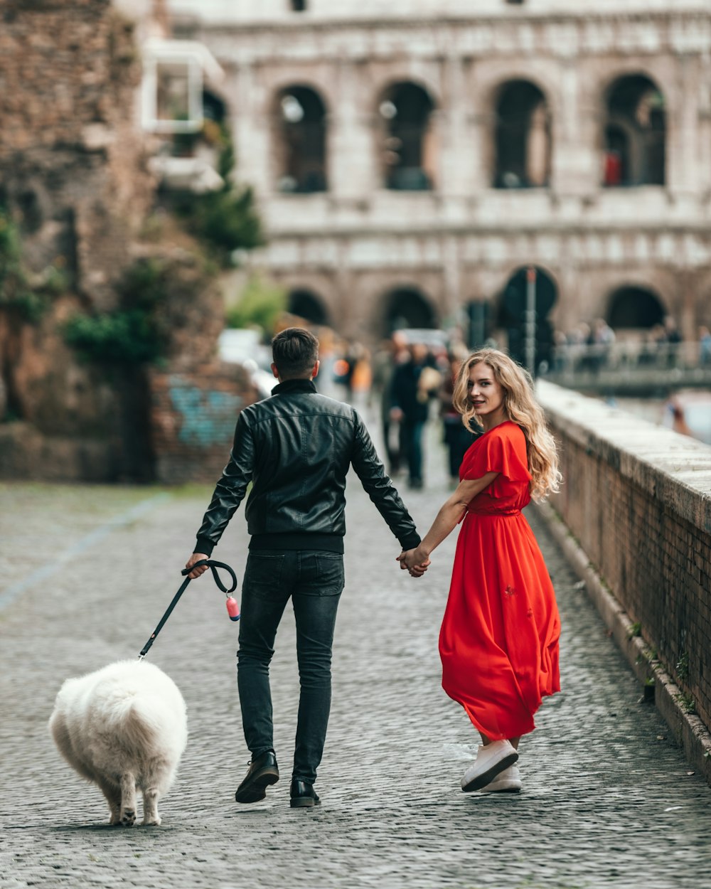 man wearing black jacket holding leash of dog and woman hand