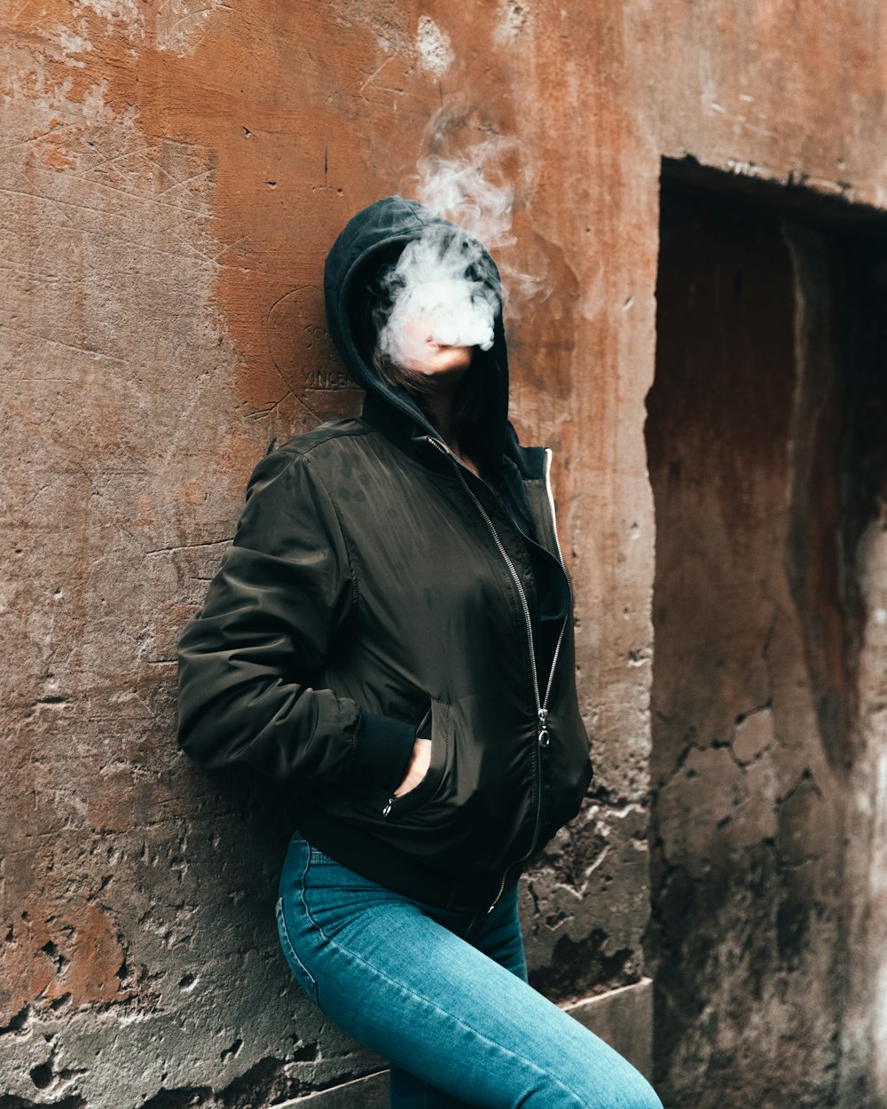 woman smoking while leaning on the wall