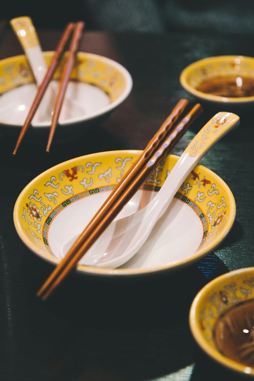 white and yellow bowl and spoon with brown chopsticks