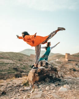 two person doing single leg balancing on stones