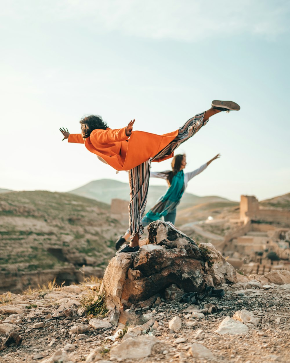 two person doing single leg balancing on stones