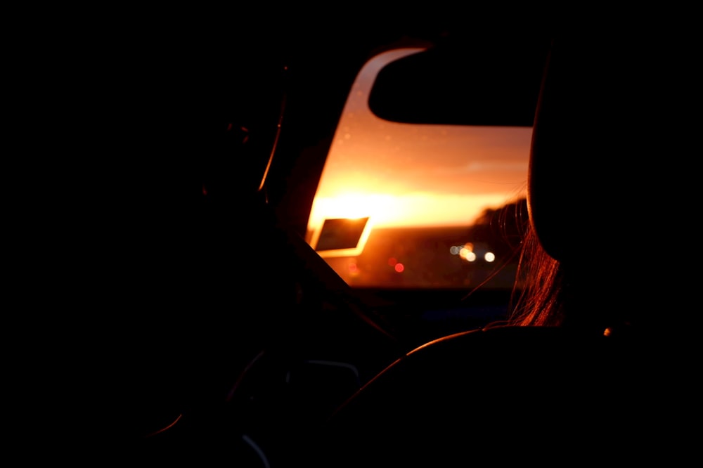 the sun is setting in the distance behind a car