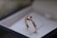 A gold ring with a single diamond set on top, presented in an elegant jewelry box with a soft, neutral background.