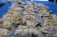 Vacuum-sealed packs of cashews, almonds, walnuts, and roasted gram neatly arranged on a wooden table.