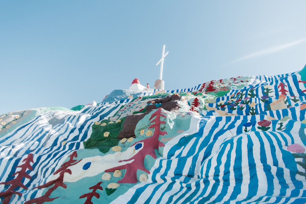 a colorfully painted hill with a cross on top of it