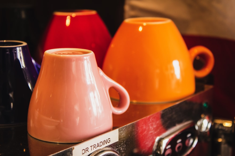 four orange and black ceramic mugs