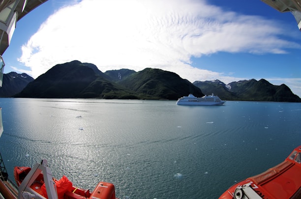 A scenic view of a cruise ship sailing through calm blue waters under a clear sky.