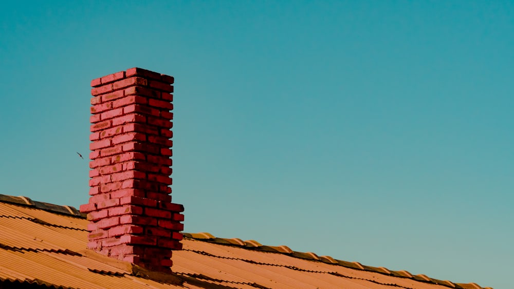Brick chimney on a shingle rooftop under a clear Texas sky