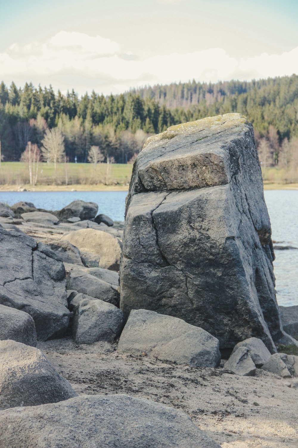 ein großer Felsen, der auf einem Sandstrand sitzt