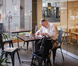 man in white shirt sitting and leaning on table