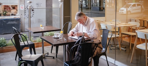 man in white shirt sitting and leaning on table