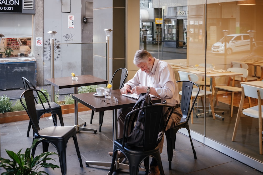 man in white shirt sitting and leaning on table