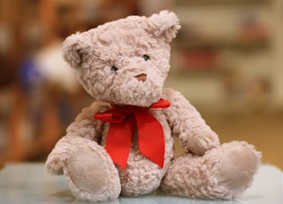 selective focus photo of brown teddy bear with red bow