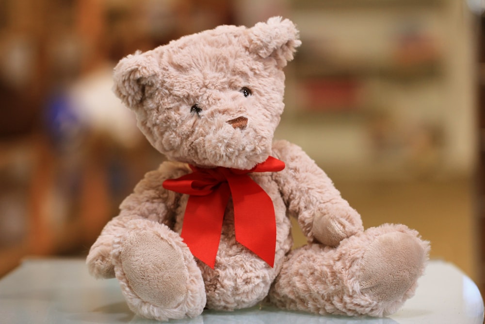 Selektives Fokusfoto eines braunen Teddybären mit roter Schleife
