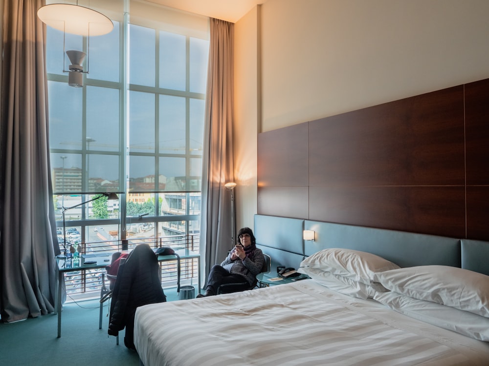 woman sitting on chair beside bed