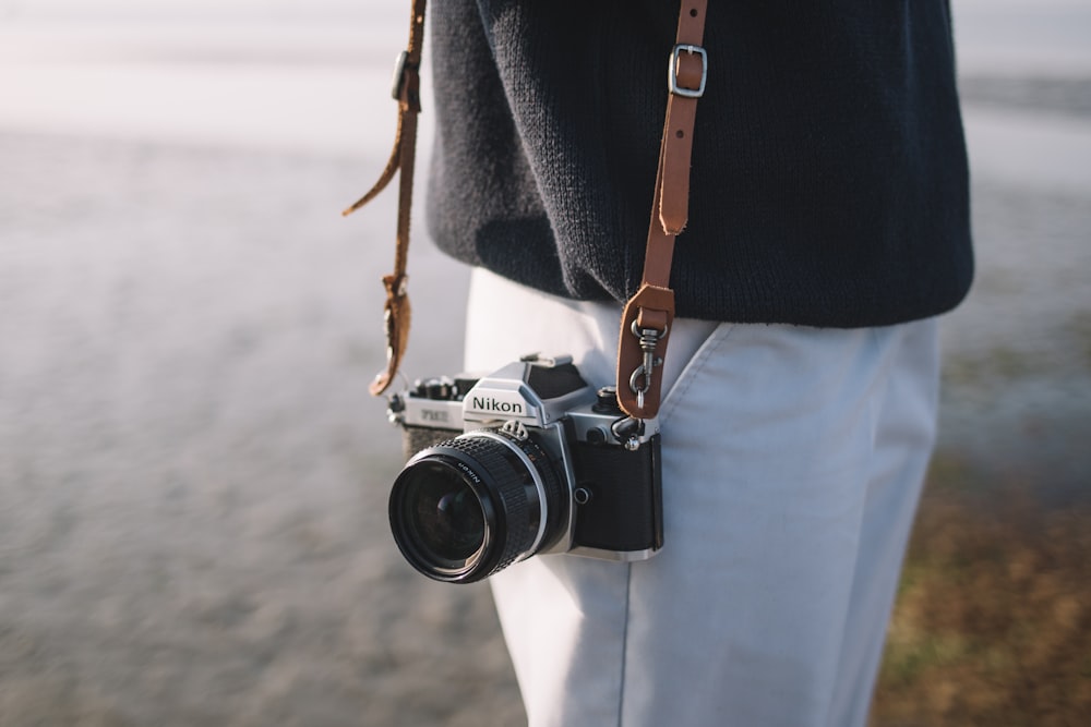 person wearing black top and white bottoms holding black camera