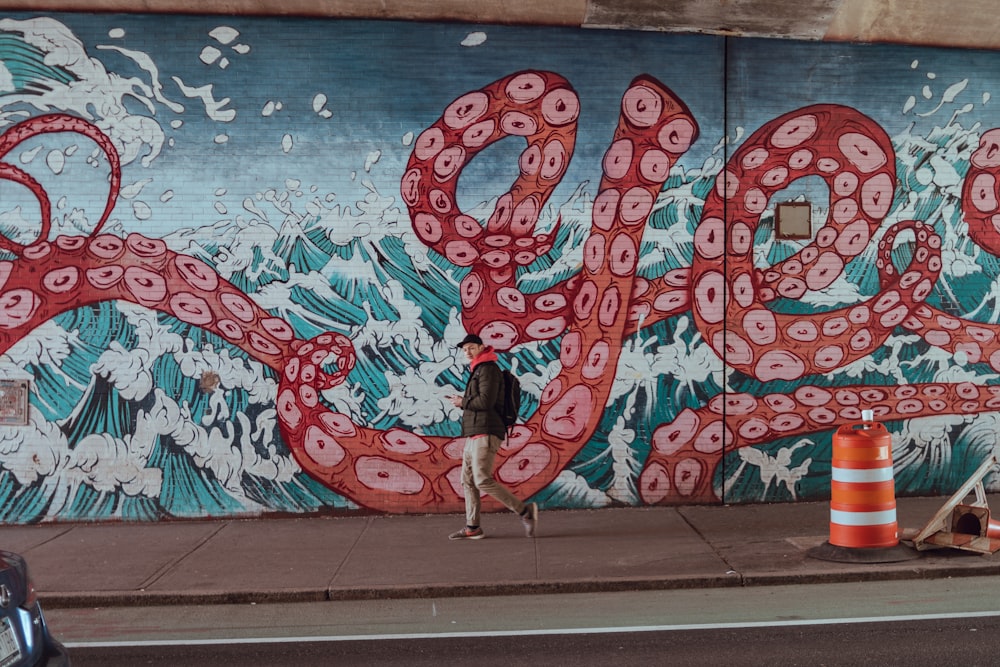 man walking beside graffiti wall