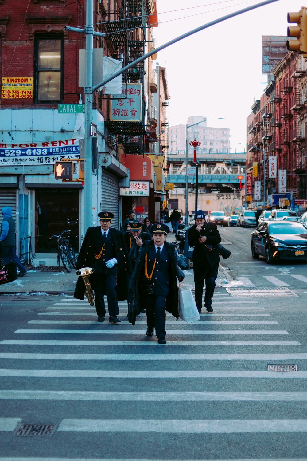 people crossing on pedestrian lane near different cars and buildings