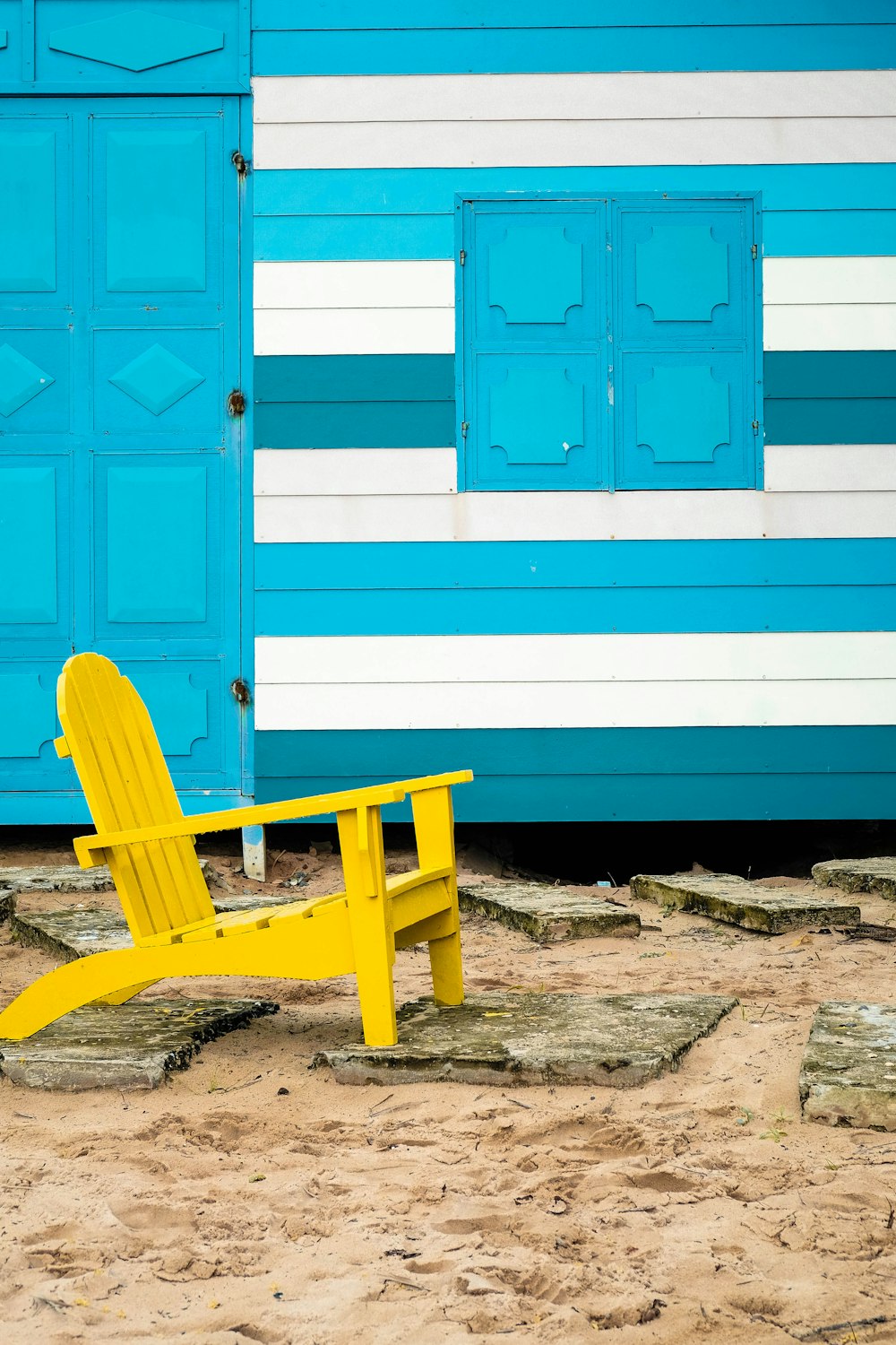 yellow wooden adirondack on brown sand