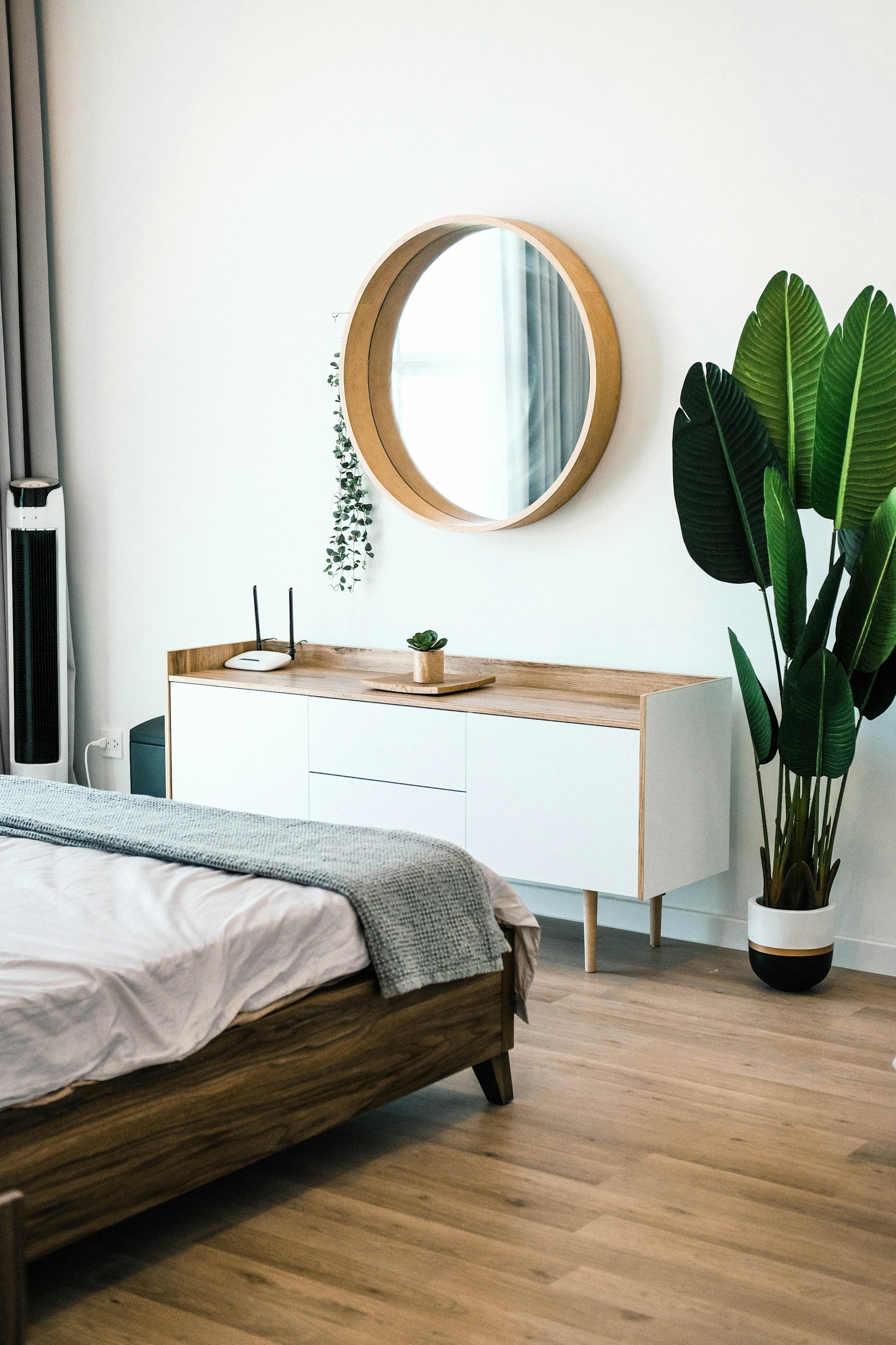 white wooden dresser with mirror, plants and a wooden bedframe