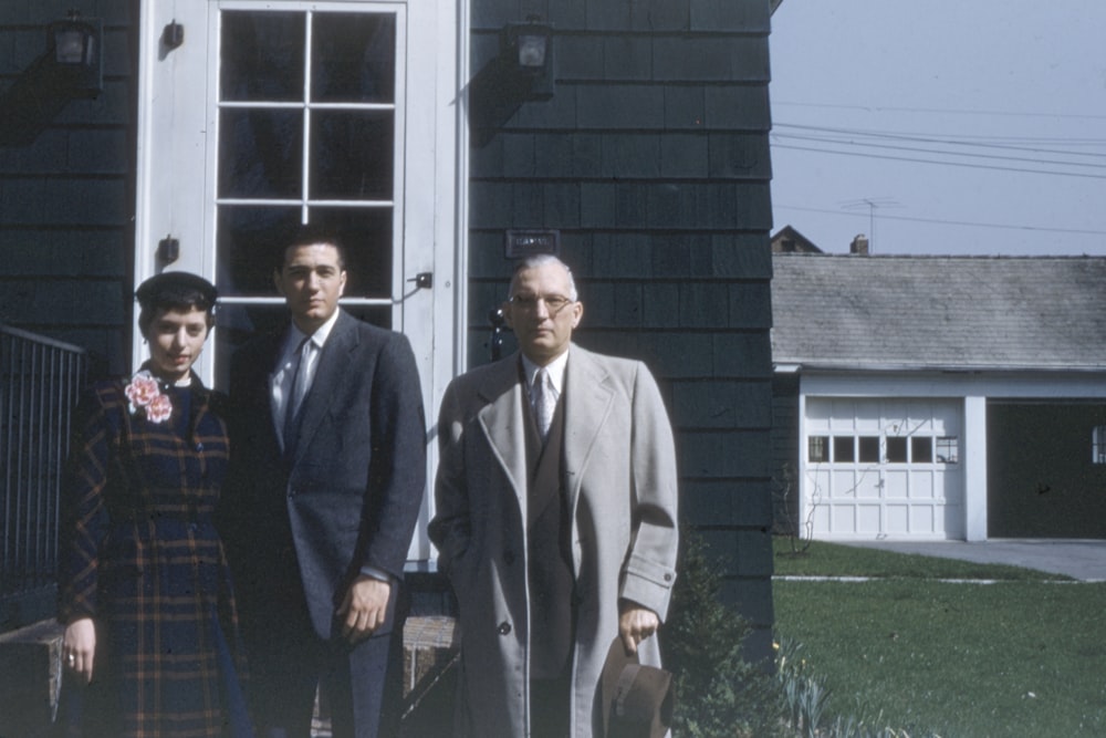 family of three standing near house door